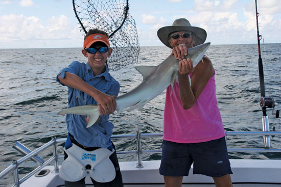 Shane Hogan is holding the tail and Capt. Judy Helmey (pink tank top) of Miss Judy Charters is holding the head of this shark, which was caught while using a  live black sea bass. As far as where did Shane hook up this fish? Right behind that shrimp boat!