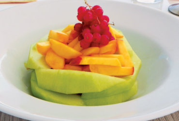 A DELICIOUS FRUIT FINISHER: Sliced melon, Sliced peaches, Sprig of cranberries. This is something very simple, but very beautiful; a presentation by Elizabeth Love.